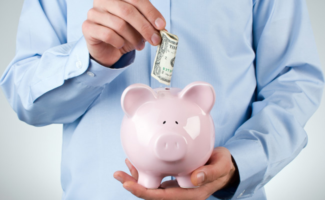 Male hand putting coin into a piggy bank